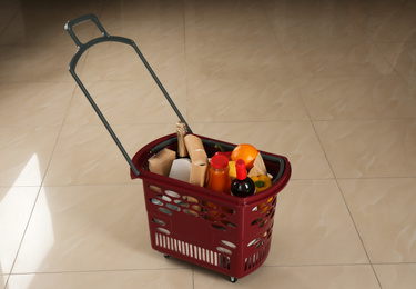 Shopping basket full of different products on beige tile floor