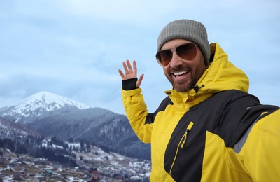 Image of Smiling man in sunglasses taking selfie in mountains