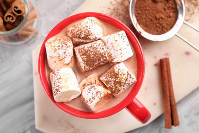 Photo of Cup of aromatic hot chocolate with marshmallows, cocoa powder and cinnamon sticks on table, top view