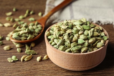Photo of Bowl of dry cardamom pods on wooden table