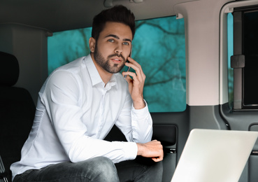 Young man talking on smartphone in modern car