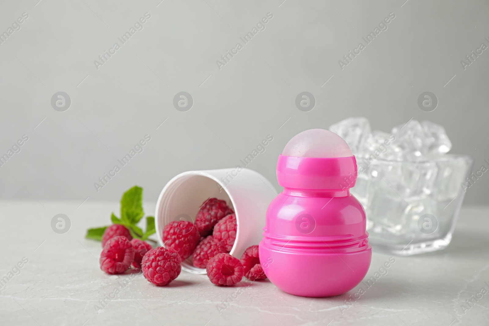 Photo of Female roll-on deodorant with raspberries and ice on light grey table