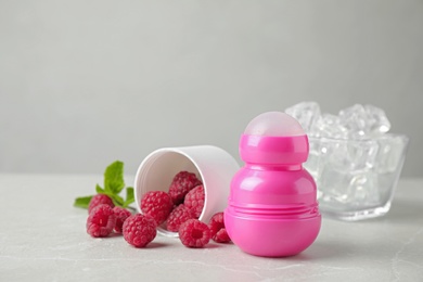 Photo of Female roll-on deodorant with raspberries and ice on light grey table