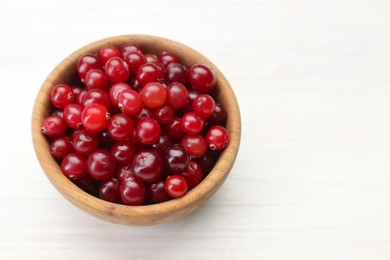 Photo of Fresh ripe cranberries in bowl on white table, above view. Space for text