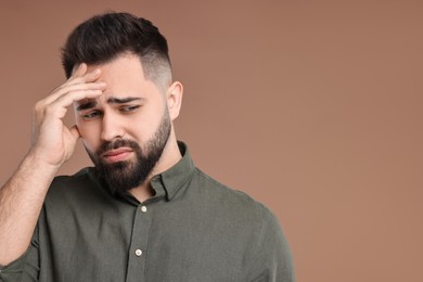 Portrait of sad man on brown background, space for text