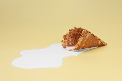 Photo of Melted ice cream and wafer cone on beige background