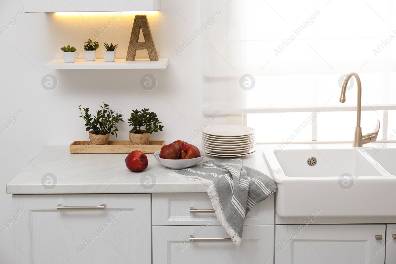 Photo of Modern kitchen interior with bowl full of ripe apples on counter