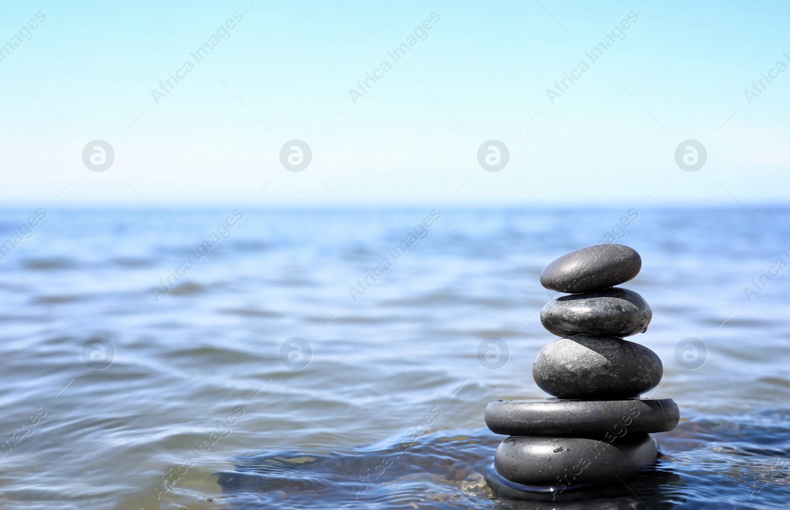 Photo of Stack of stones in sea water, space for text. Zen concept