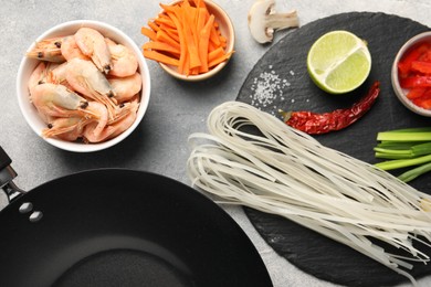 Flat lay composition with black wok, spices and products on grey textured table