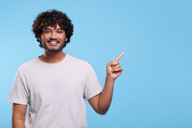 Handsome smiling man on light blue background, space for text