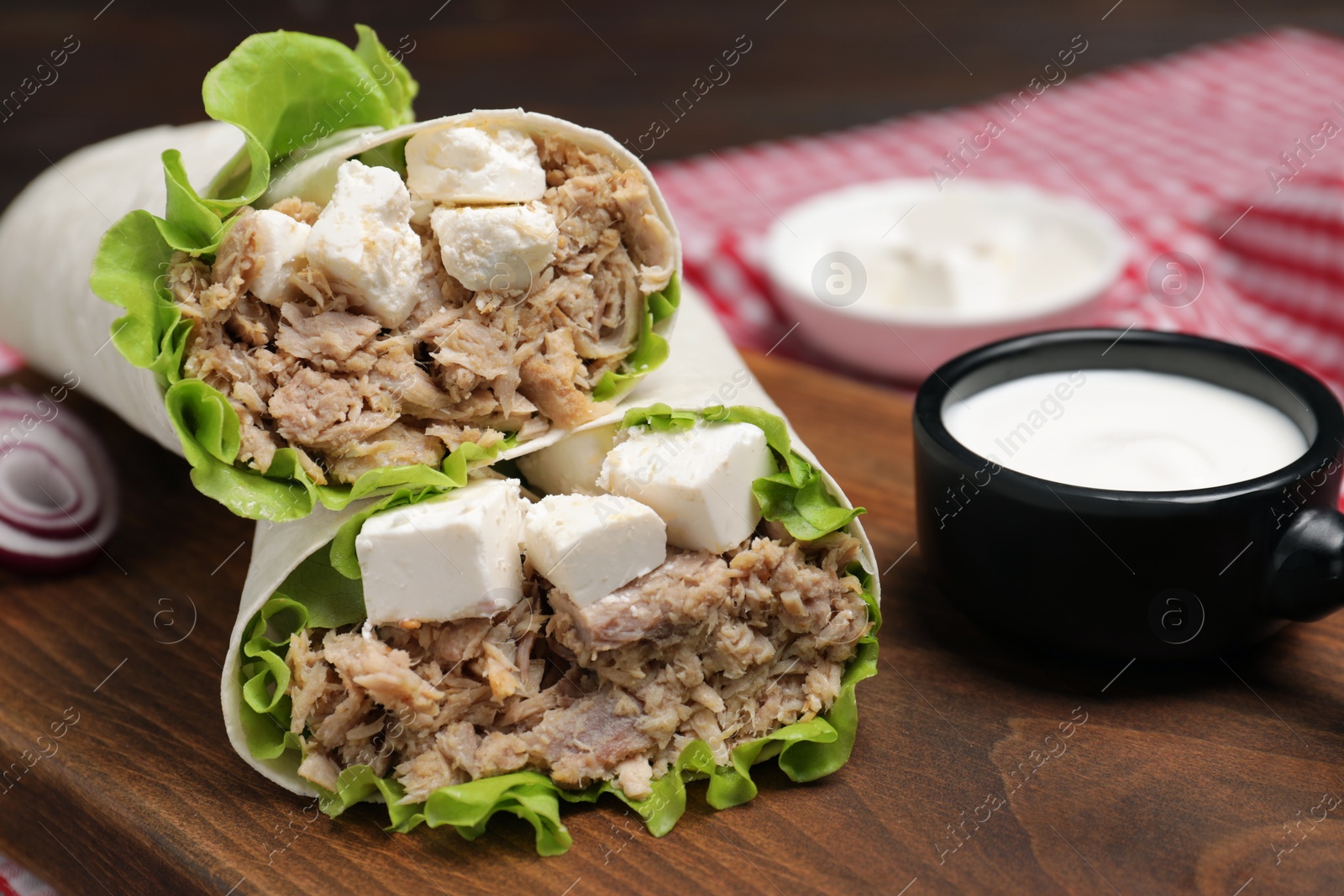 Photo of Delicious tortilla wraps with tuna on wooden board, closeup