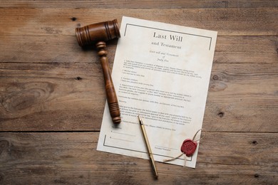 Photo of Last Will and Testament with wax seal, gavel and pen on wooden table, top view