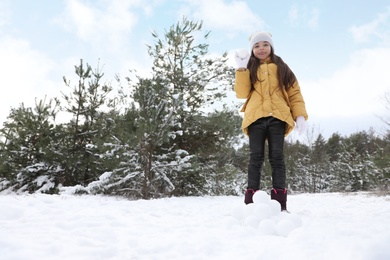 Photo of Cute little girl with snowballs in winter forest