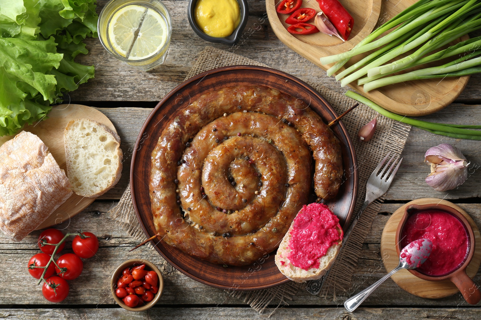 Photo of Tasty homemade sausages served on wooden table, flat lay