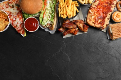 Photo of Burger, pizza and other fast food on black table, flat lay with space for text