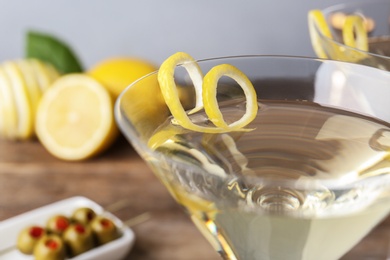 Photo of Glasses of lemon drop martini cocktail with zest on table against grey background