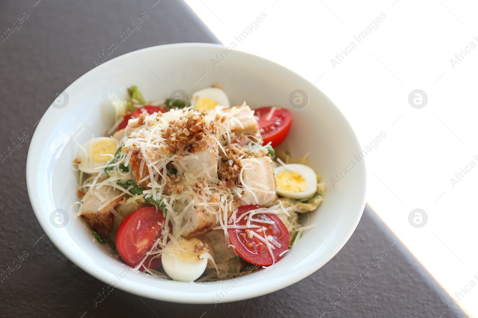 Photo of Delicious Caesar salad in bowl on table