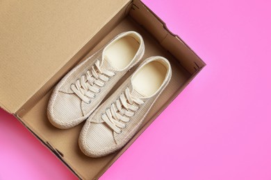 Photo of Comfortable shoes in cardboard box on pink background, top view. Space for text