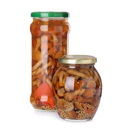 Jars with marinated mushrooms on white background