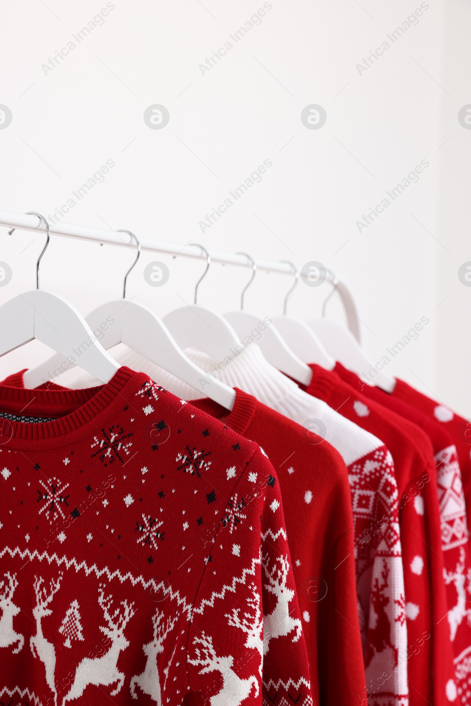 Photo of Rack with different Christmas sweaters on white background