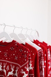 Rack with different Christmas sweaters on white background