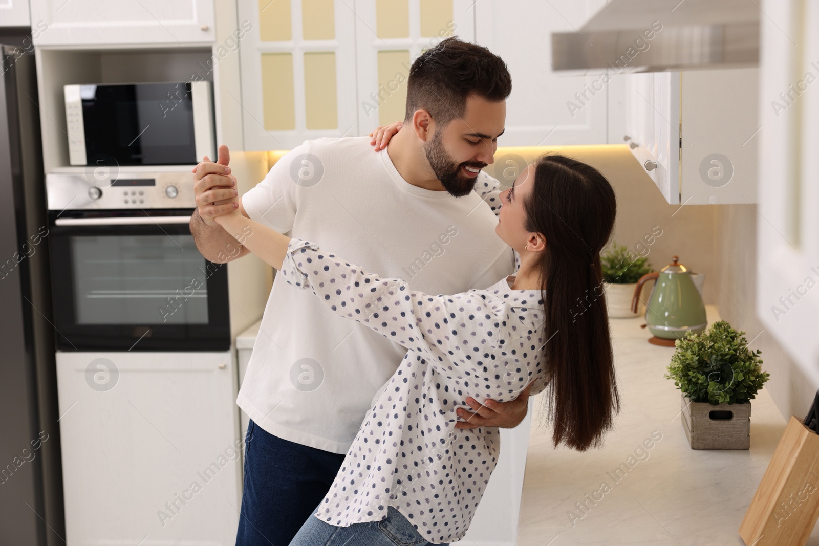 Photo of Happy lovely couple dancing together in kitchen