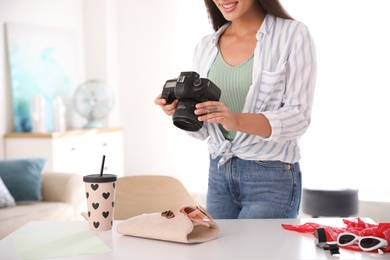 Photo of Young photographer taking picture of accessories indoors, closeup