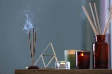 Incense sticks smoldering on wooden table indoors, space for text