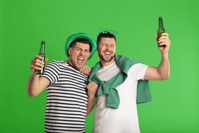 Image of Men in St.Patrick's Day outfits with beer on green background