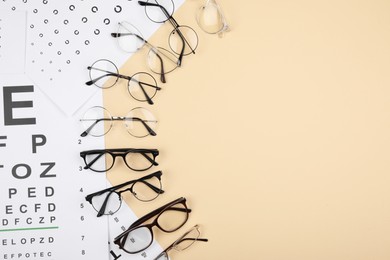 Photo of Vision test chart and glasses on beige background, flat lay. Space for text