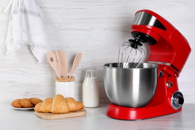 Photo of Modern red stand mixer, croissant, cookies and milk on white marble table