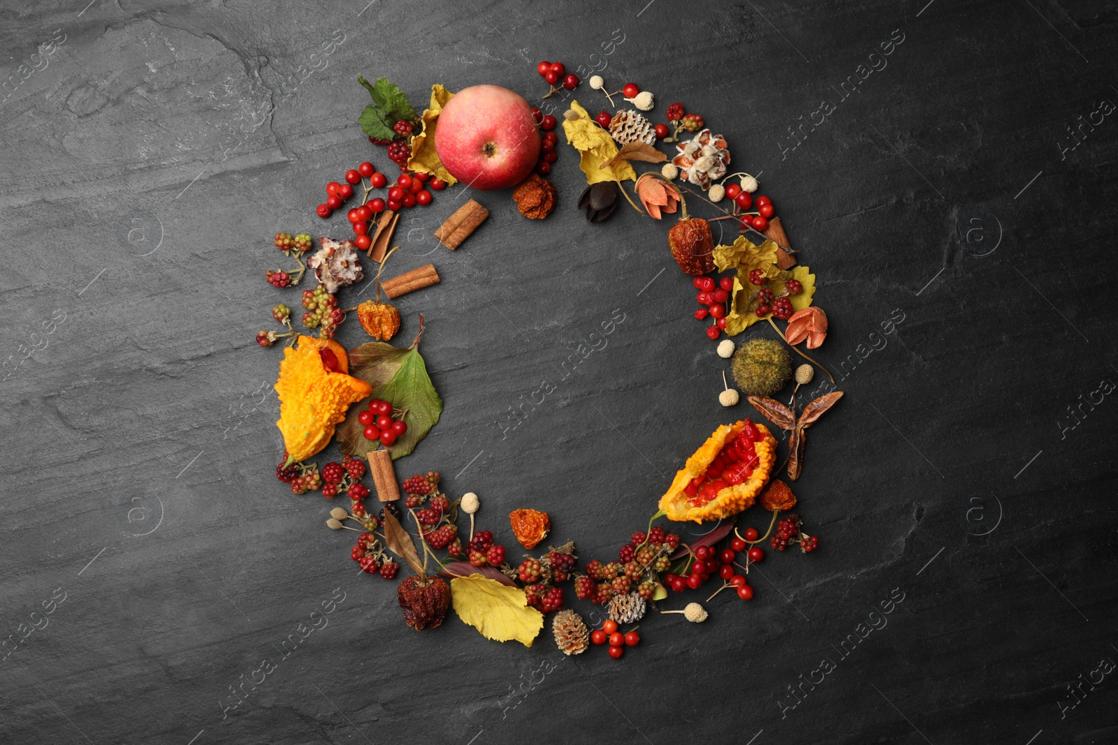 Photo of Dried flowers, leaves and berries arranged in shape of wreath on black background, flat lay with space for text. Autumnal aesthetic