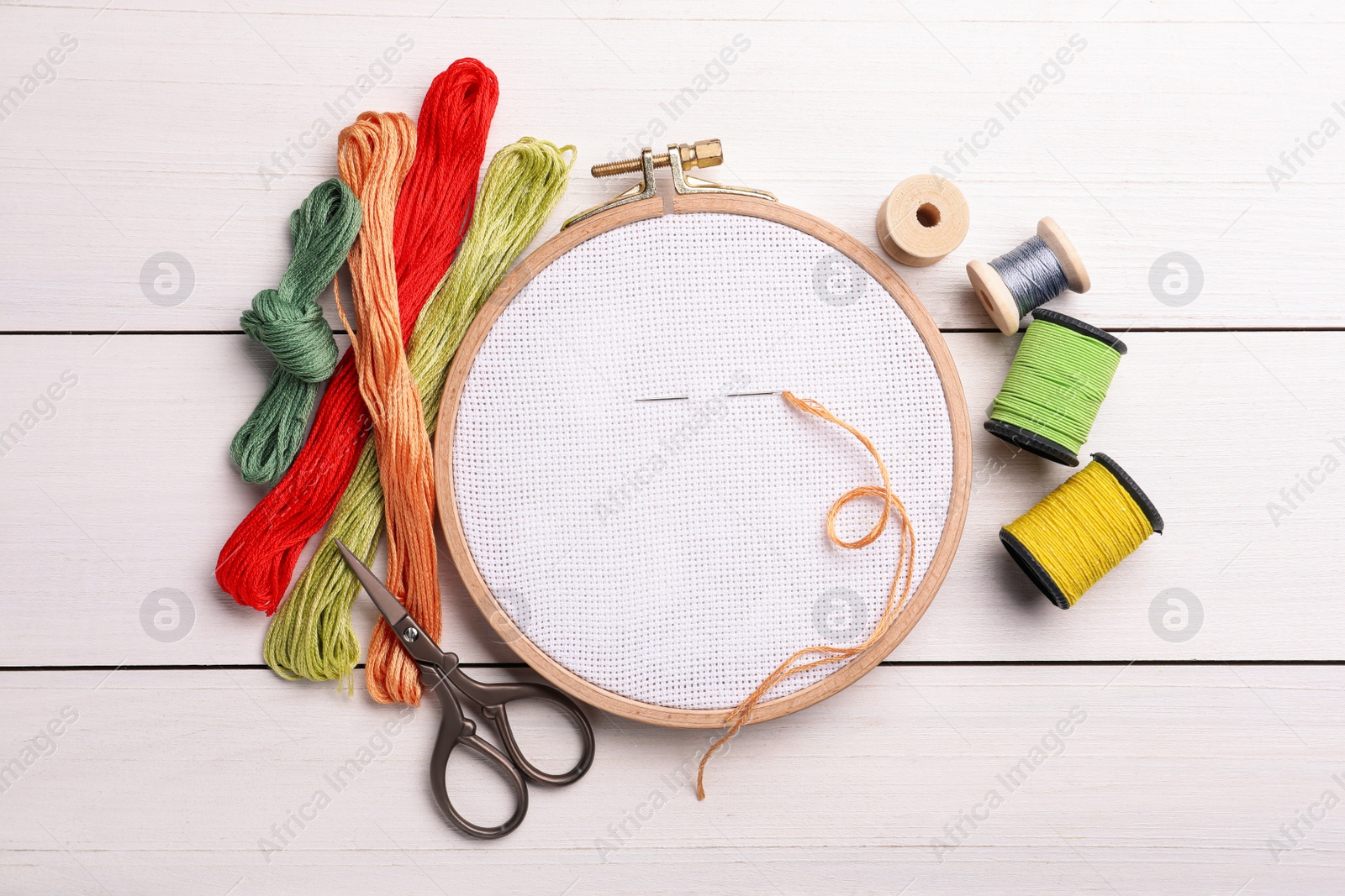 Photo of Set of embroidery equipment on white wooden table, flat lay