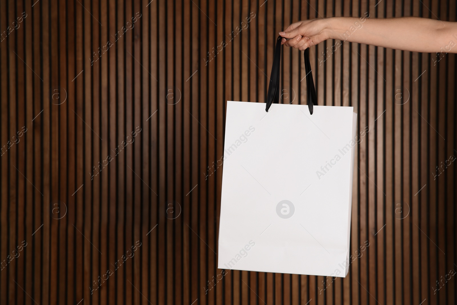 Photo of Woman holding paper shopping bag on wooden background. Mock up for design