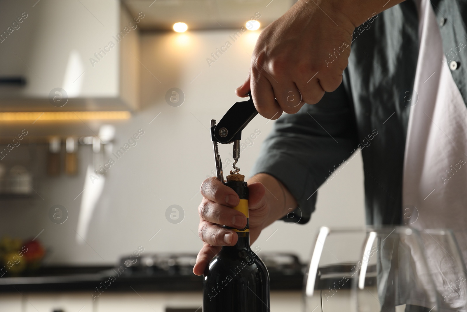 Photo of Man opening wine bottle with corkscrew indoors, closeup. Space for text