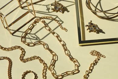 Metal chains and other different accessories on beige background, above view. Luxury jewelry