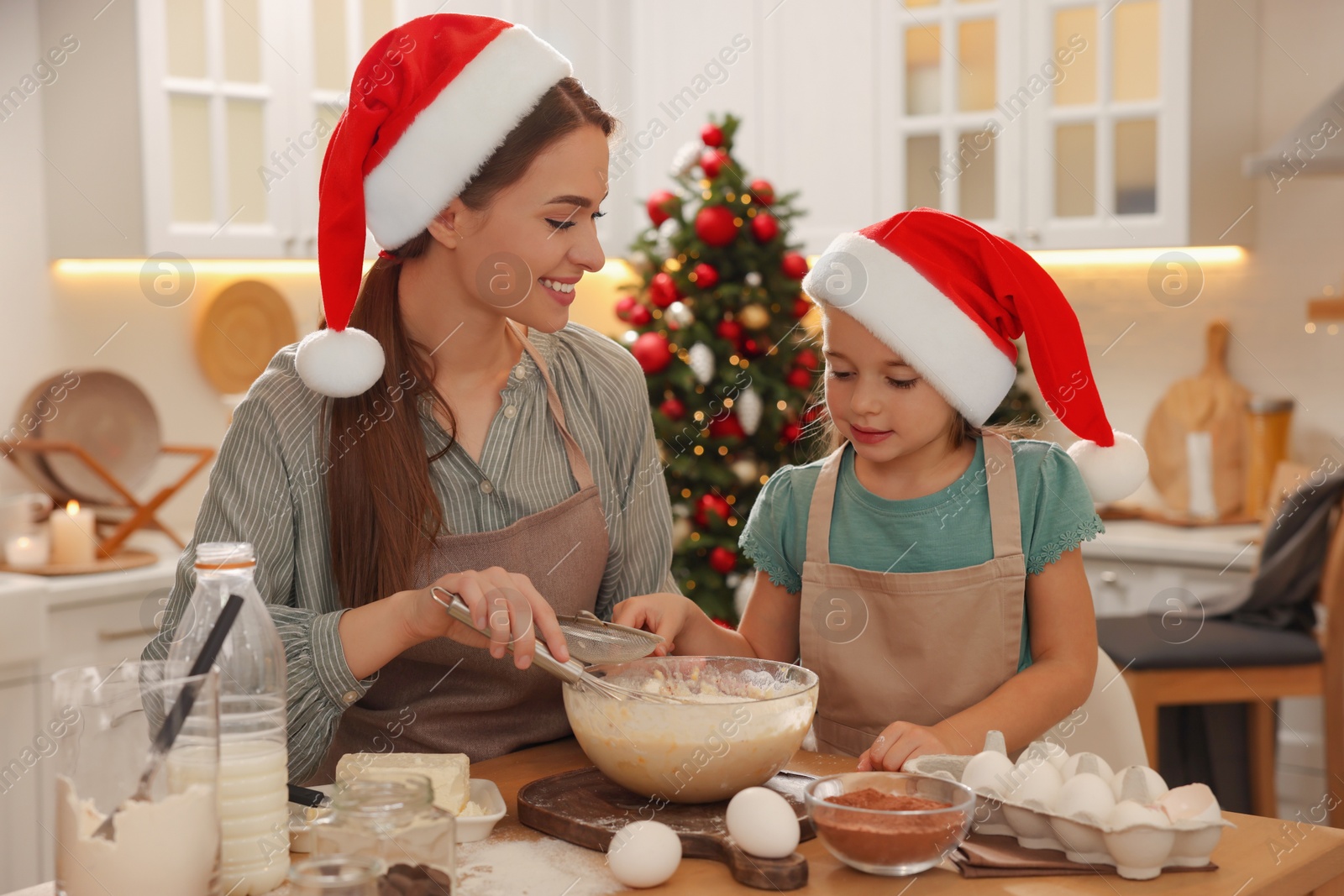 Photo of Mother with her cute little daughter making dough for Christmas cookies in kitchen