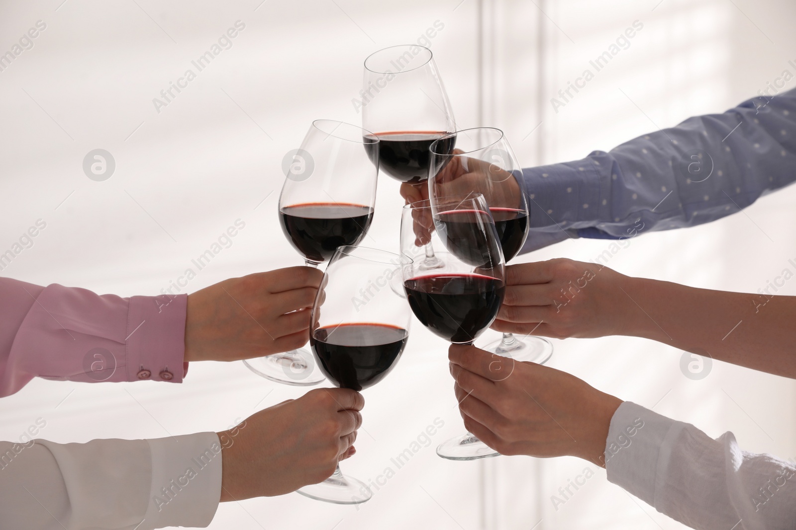 Photo of People clinking glasses of wine on white background, closeup