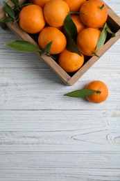 Photo of Crate with fresh ripe tangerines and space for text on wooden background, top view