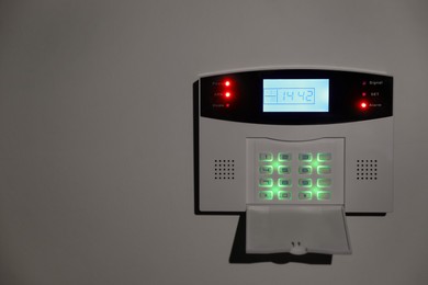 Photo of Home security alarm system on white wall, space for text