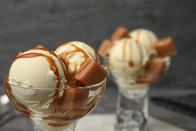 Photo of Delicious ice cream with caramel and sauce served on table, closeup. Space for text