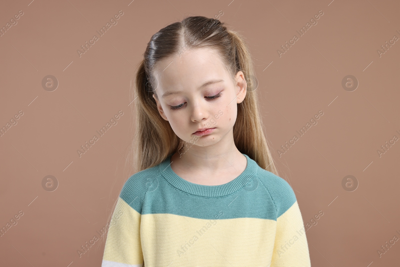 Photo of Portrait of sad girl on light brown background