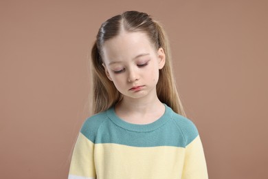 Portrait of sad girl on light brown background