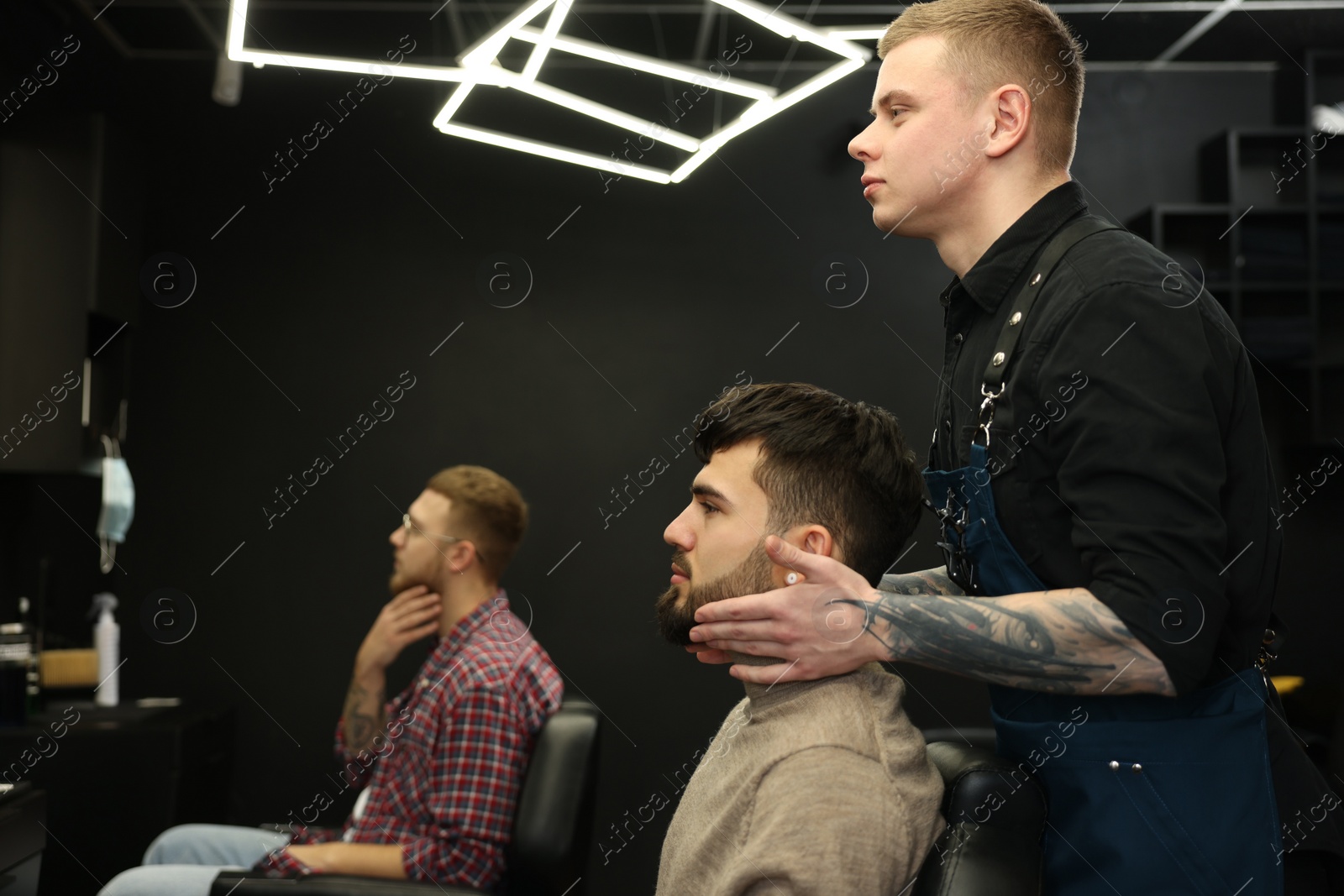 Photo of Professional hairdresser working with bearded client in barbershop