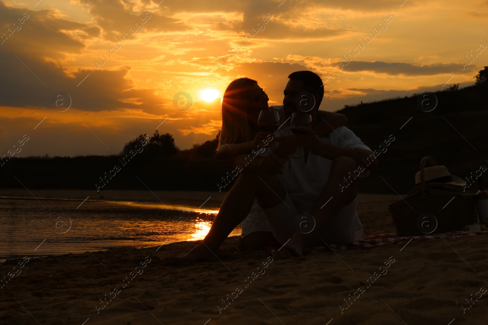 Photo of Happy romantic couple drinking wine together on beach