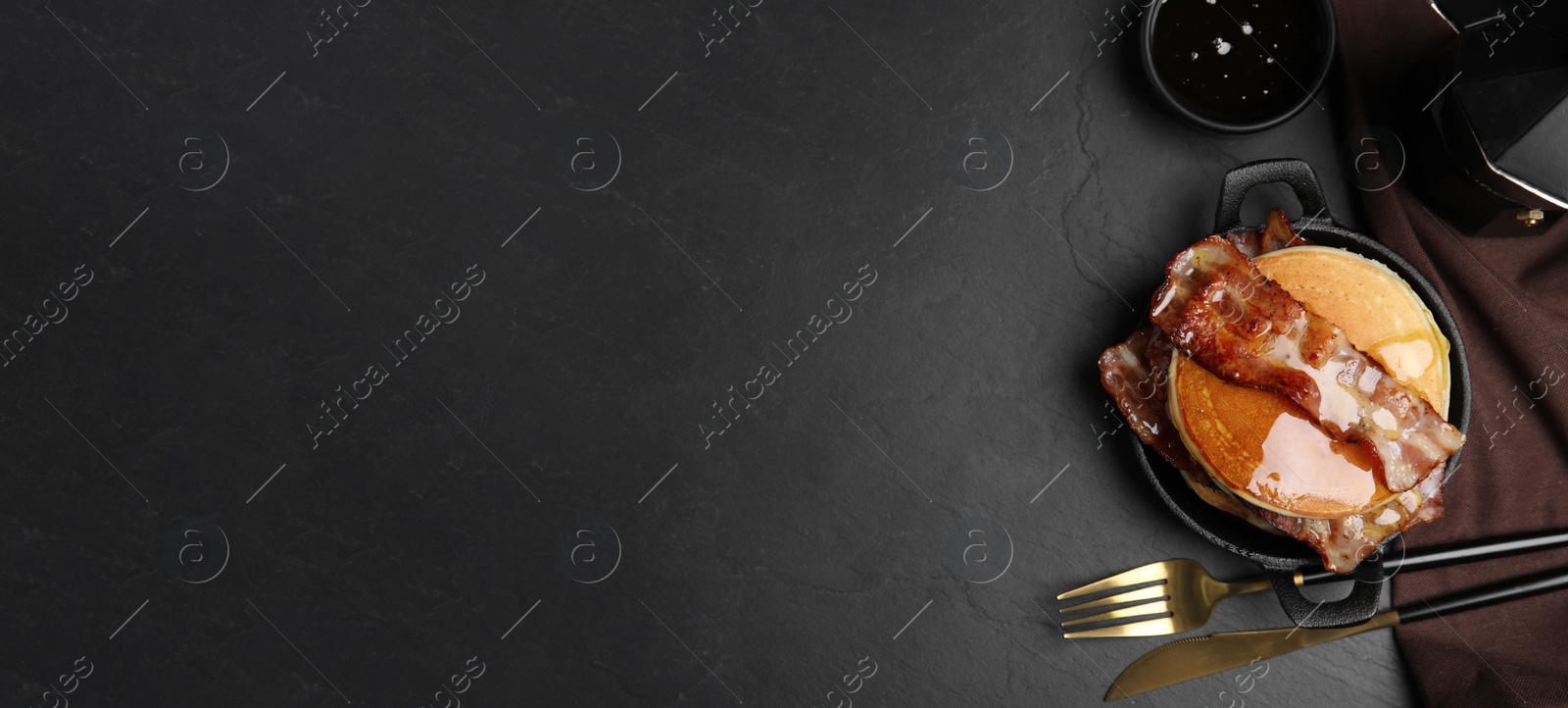 Image of Delicious pancakes with maple syrup and fried bacon on black table, flat lay with space for text. Banner design