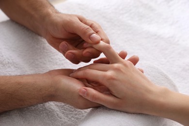Photo of Woman receiving hand massage on soft towel, closeup