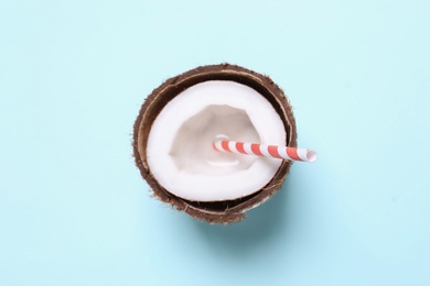 Photo of Halved coconut with straw on light blue background, top view