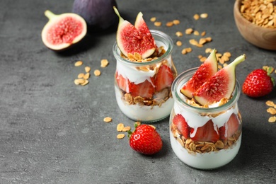 Photo of Jars of tasty homemade granola dessert on grey table. Healthy breakfast