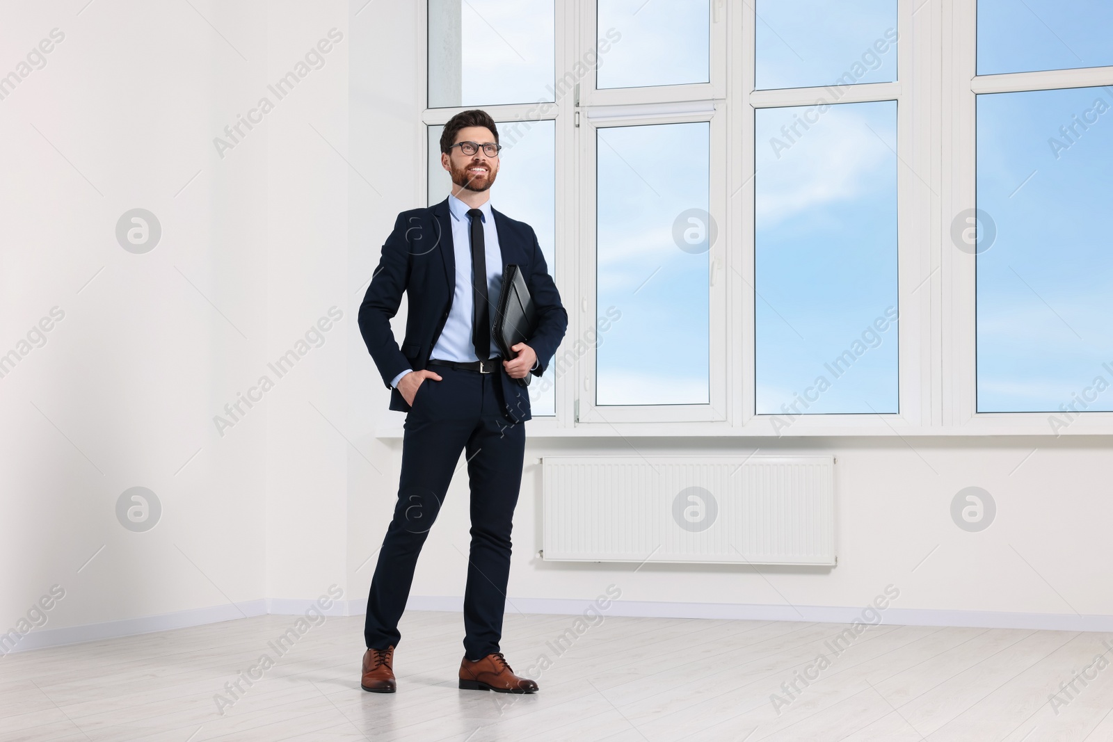 Photo of Handsome real estate agent with documents in empty room, space for text